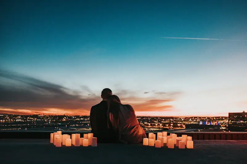 Couple sitting among candles above city lights