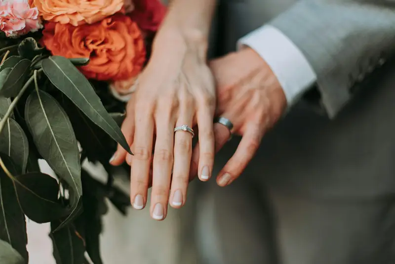 Close-up of hands with wedding rings and florals