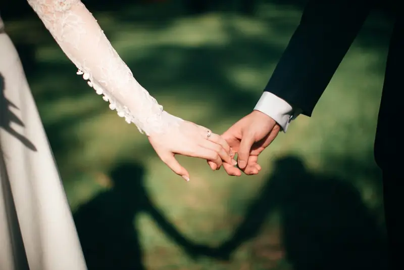 Couple holding hands with shadows on the grass