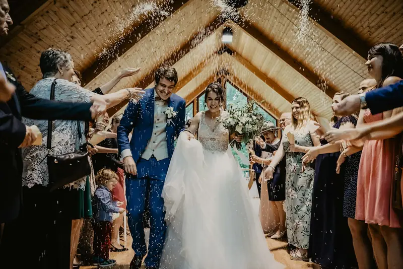 Guests throwing petals as newlyweds walk down the aisle
