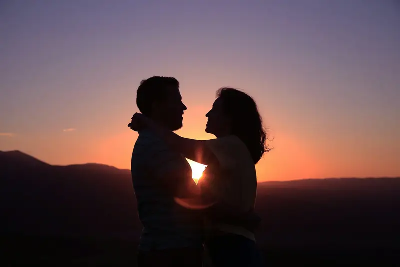 Couple silhouetted against a sunset