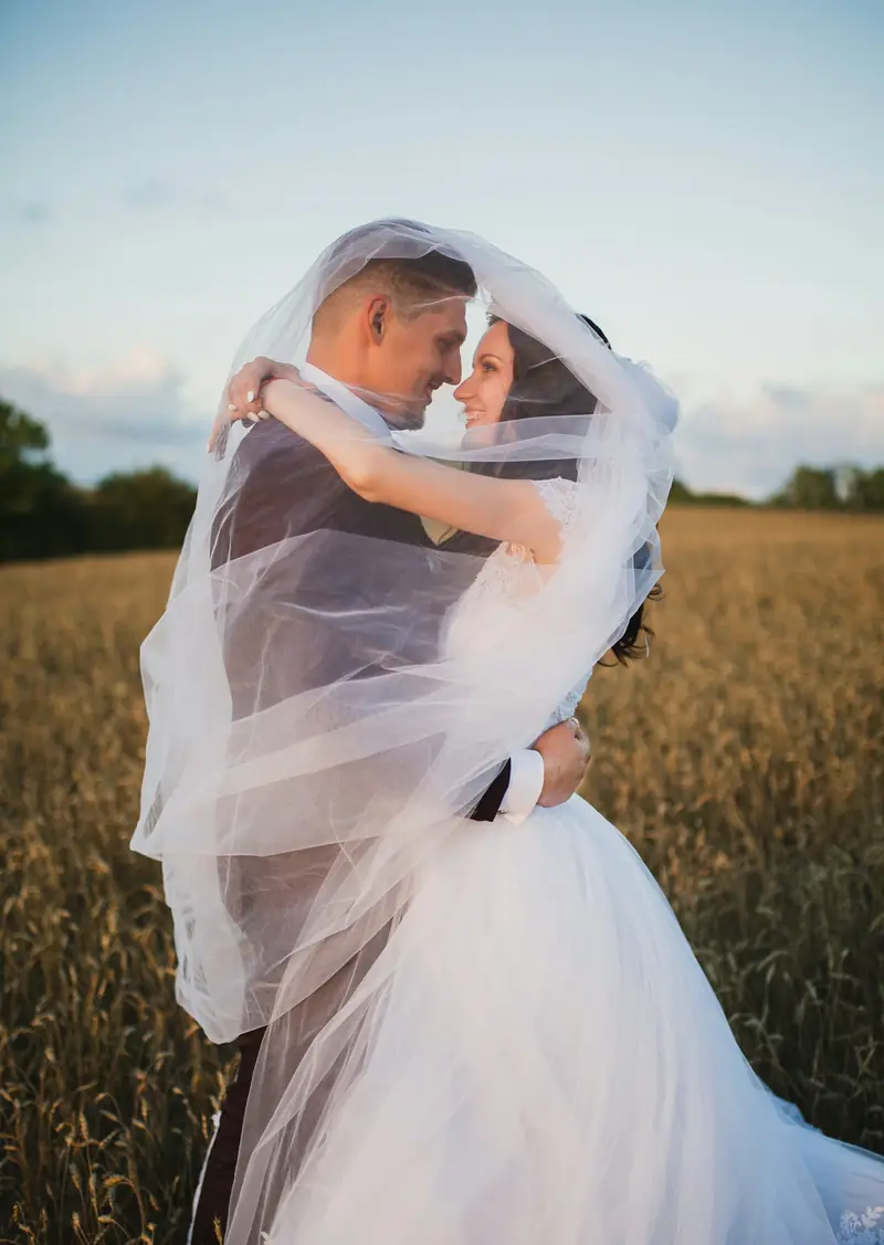 Couple embracing under a veil in a field